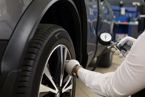 Ignore These 5 Whimsical Myths About Tires | Kanuga Tire & Auto in Hendersonville, NC. Image of a technician checking the tire pressure of a car.