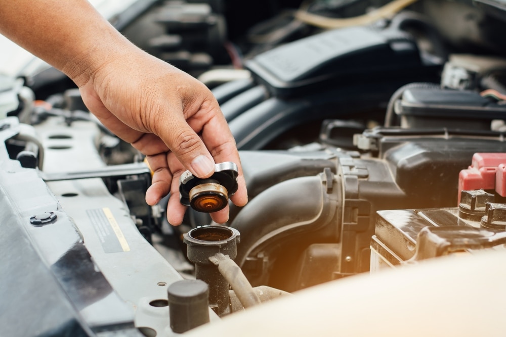 Coolant System Check in Hendersonville NC At Kanuga Tire & Auto. Mechanic checking a vehicle radiator during a coolant service
